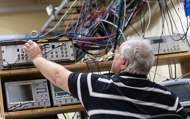 En gråhårig man som sträcker sig mot en apparat på en hylla