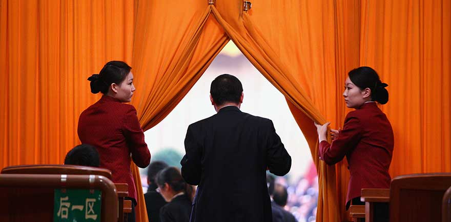 Två kinesiska kvinnor släpper in en man på en scen.