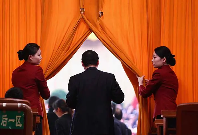 Two women opening a curtain for a man.